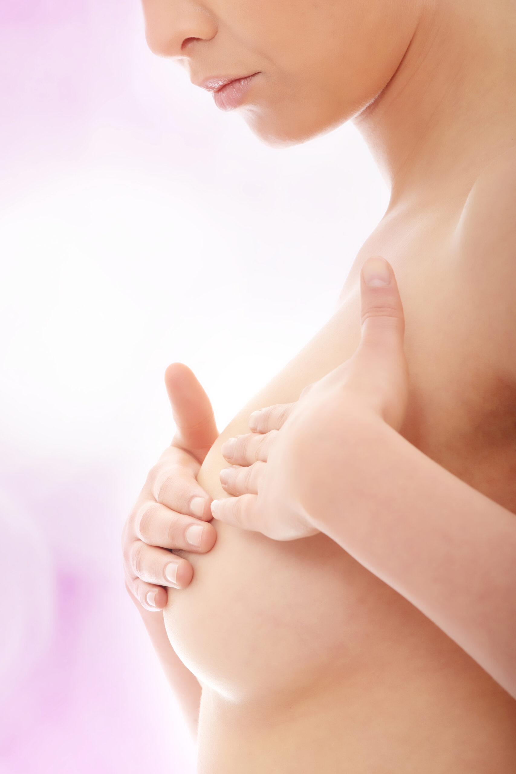 Young Caucasian adult woman examining her breast for lumps or signs of breast cancer